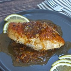 a piece of chicken covered in gravy with lemon slices