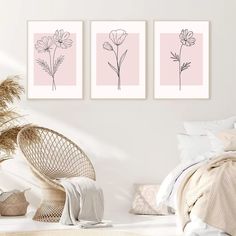 three pink flower prints on a white wall above a bed and wicker chair in a bedroom