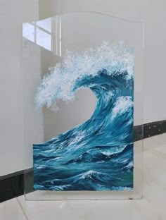 an acrylic painting of a wave in the ocean is displayed on a glass block