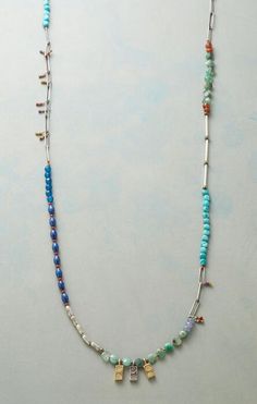 a necklace with beads and charms hanging from it's side on a white surface