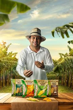 a man standing in front of two bags of bananas on a wooden table with palm trees behind him