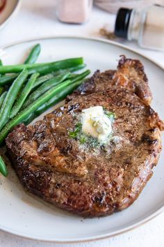 a steak and green beans on a white plate