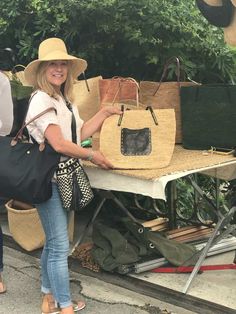 a woman standing next to a table with bags on it and another person holding a bag