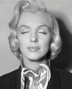 a black and white photo of a woman with her eyes closed wearing a bow tie