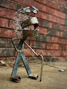 a metal figure is standing in front of a brick wall and holding onto a handlebar