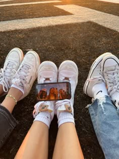 two people sitting on the ground with their legs crossed and one holding a cell phone