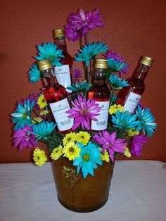 a vase filled with bottles and flowers on top of a table