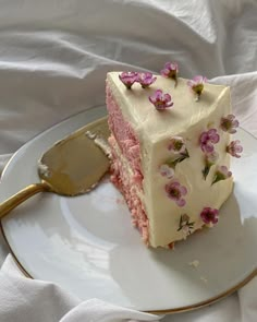 a piece of cake with white frosting and pink flowers on it sitting on a plate