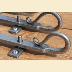 two metal hooks sitting on top of a wooden table