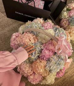 a basket filled with pink and blue flowers on top of a floor next to a box