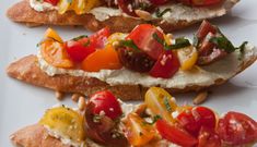 three pieces of bread with tomatoes and other vegetables on them sitting on a white plate