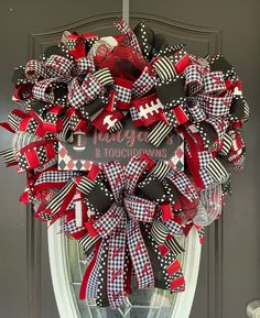 a football wreath on the front door with black, red and white bows hanging from it