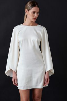 a woman wearing a white dress with bell sleeves