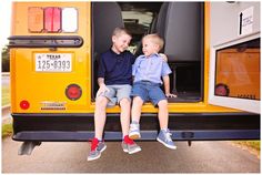 two young boys sitting on the back of a school bus