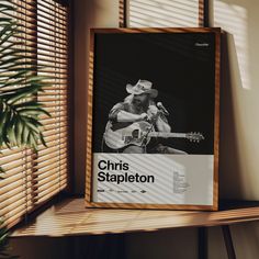 a poster with a man playing the guitar on top of a shelf next to a window