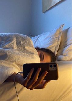 a woman is laying in bed and looking at her cell phone with the light on