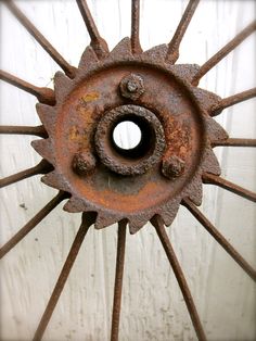 an old rusted metal wheel on the side of a building