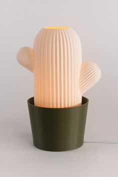 a white cactus lamp sitting on top of a green pot