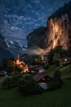 a village in the mountains at night with lights shining on it's steeps