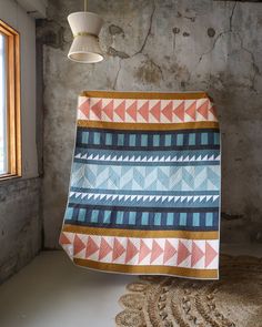 a blue and orange blanket hanging from the ceiling next to a light fixture in a room