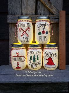 four jars with christmas decorations painted on them