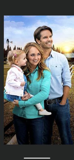 a man and woman holding a baby standing next to each other