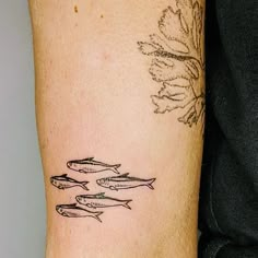 a woman's arm with three fish on it and a flower tattoo design in the middle