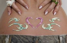 a woman's stomach with different colored jewels on her belly and the word love written in it