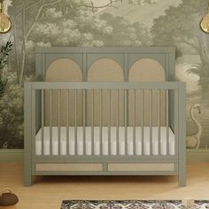 a baby crib in front of a wall mural