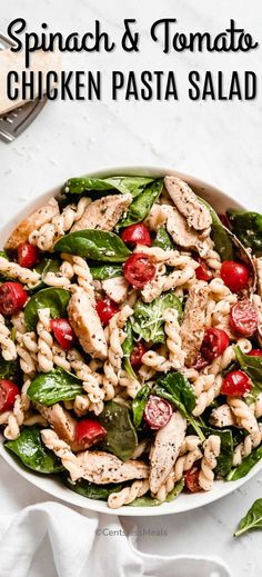 spinach and tomato chicken pasta salad in a white bowl