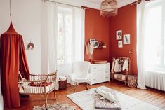 a room with red walls, white furniture and wooden flooring is pictured in this image