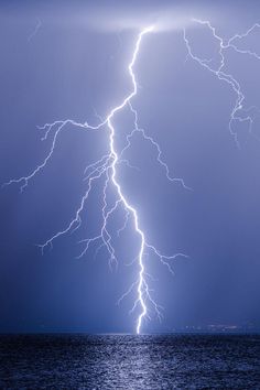 lightning strikes over the ocean on a cloudy day