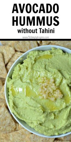 avocado hummus in a bowl with tortilla chips on the side