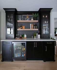 a kitchen with black cabinets and shelves filled with bottles, drinks and glasses on the counter