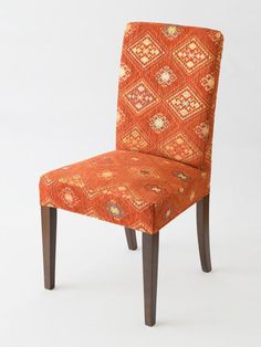 an orange patterned chair with wooden legs