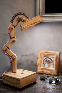 a wooden robot lamp sitting on top of a table next to a pair of glasses