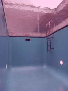 an empty swimming pool with ladders to the ceiling and water in the back ground