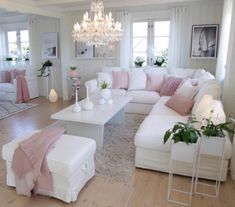 a living room filled with furniture and a chandelier hanging above the couches