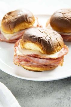 three ham and cheese sandwiches on a white plate