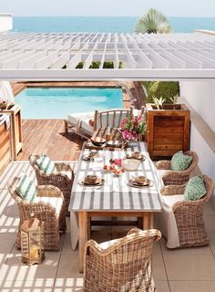 an outdoor dining area with wicker chairs and table next to the swimming pool,