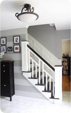 there is a white stair case in the room with pictures on the wall behind it