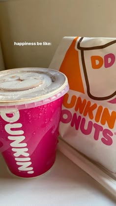 a pink dunkin donuts cup sitting next to a bag