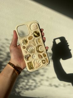 a person holding up a cell phone case with shells on it's back cover