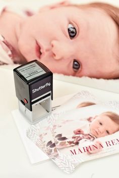 a baby laying on top of a table next to a stamper