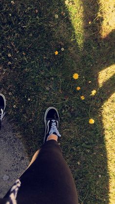 a person standing on top of a lush green field next to a yellow dandelion