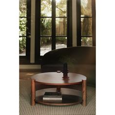 a coffee table with a book on it in front of some windows