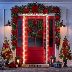 a red door decorated with christmas wreaths and lights