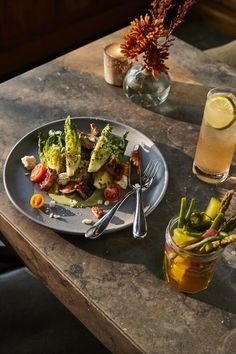 a plate of food on a table next to a glass of water and a drink