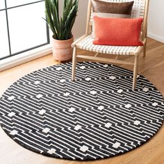 a black and white area rug with an orange pillow in the corner next to a chair