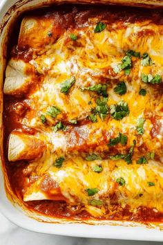 an enchilada casserole in a white dish with cheese and green garnish